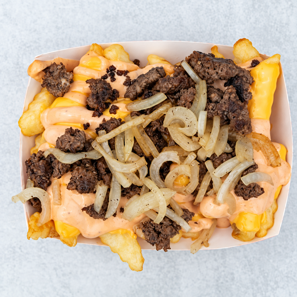 Loaded fries topped with melted cheese, creamy orange sauce, crispy beef crumbles, and grilled onions in a takeout tray.